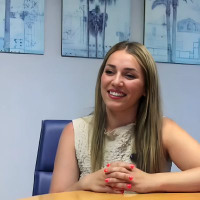 Headshot of Irene Santiago Padilla, Web Developer, smiling and sitting at a desk.